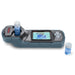 Ohaus Aquasearcher AP50MM Colorimeter Sitting on Flat Surface Left Side Top Front with 10ml Vial Filled with Blue Liquid in Vial Compartment One Blue Liquid Filled 10ml Vial is Sitting to the Right Side 